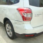 Before and after photographs of a damaged white Subaru that was repaired by Elite Paint & Body Shop in West Palm Beach, Florida
